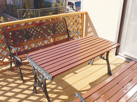 家族4人で色を塗ったというテーブルとベンチが置かれた明るいウッドデッキ